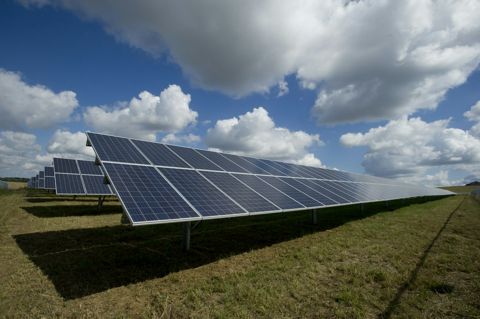 Utility-scale solar farm at dawn with battery storage units and distant mountain range